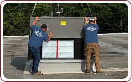Two Anderson Heating and Cooling technicians installing commercial HVAC on rooftop of building Central Kentucky